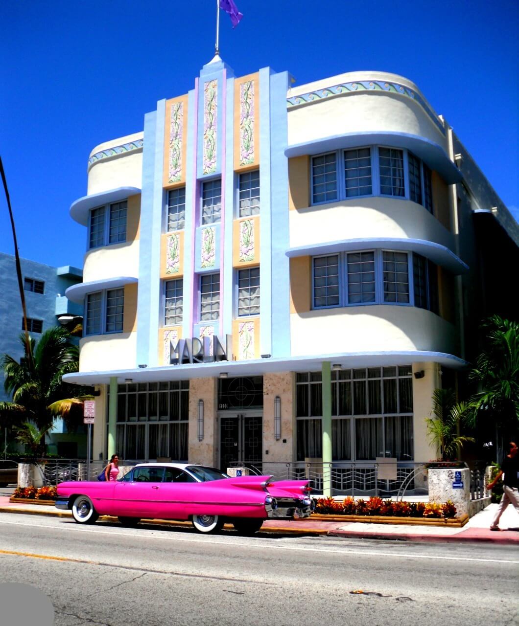 Blocky three-story building with a hot-pink sports car parked out front.