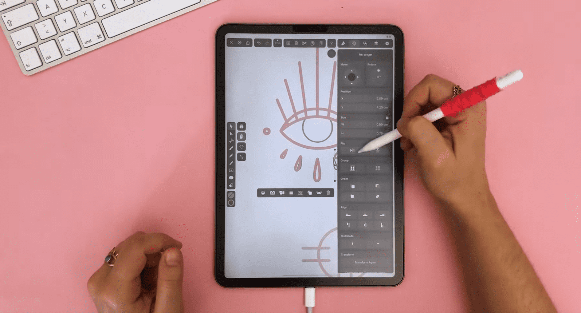 Female hands drawing on iPad with a pink background.