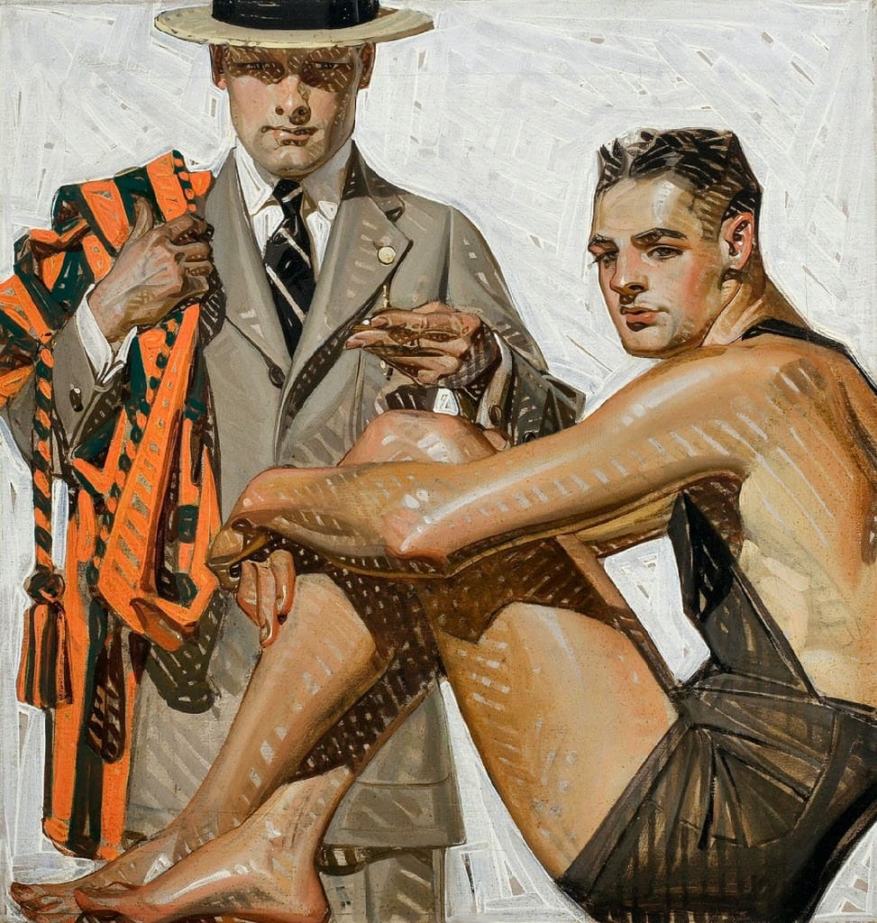 Two young men, one standing, one sitting in a bathing suit. 