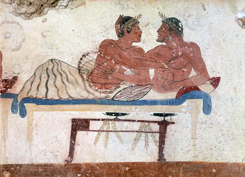 Two Greek men embracing on a canapé. 