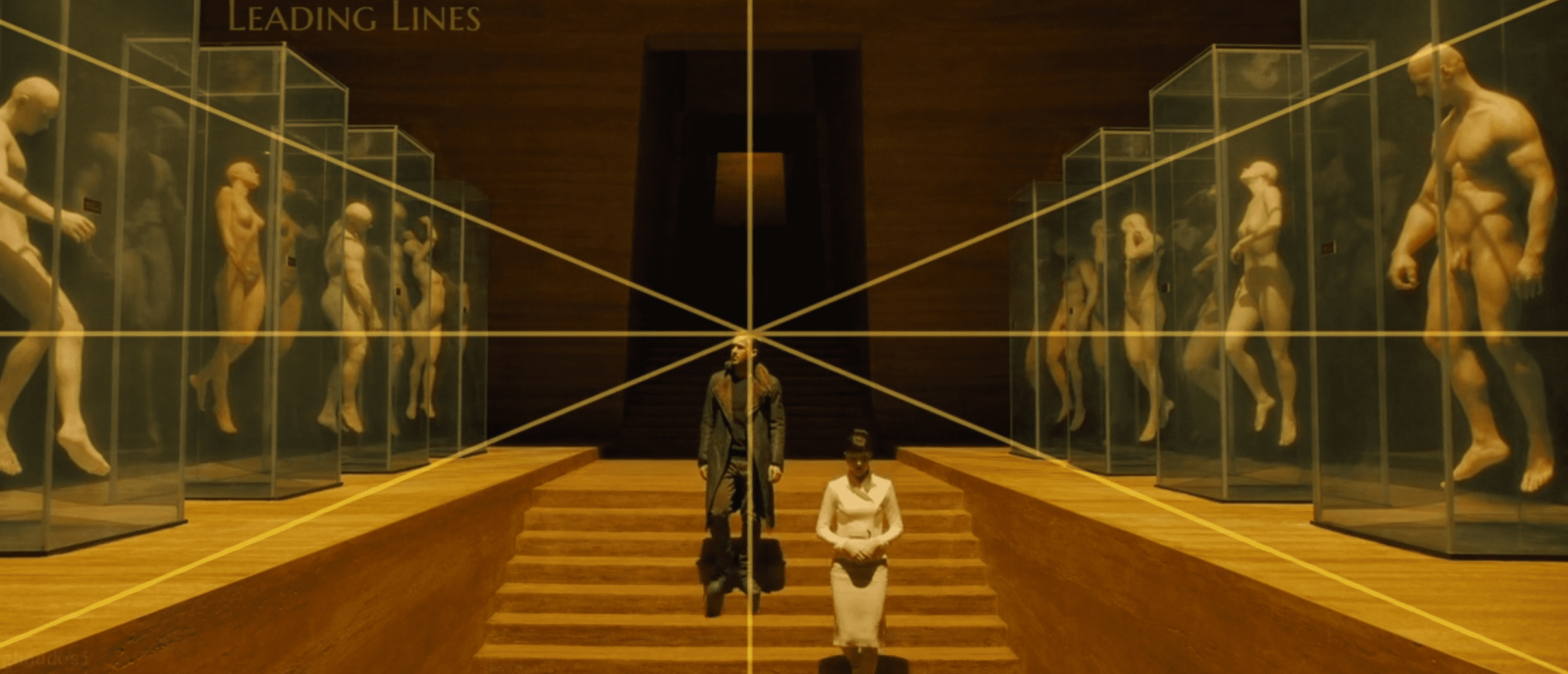 Man and woman descending stairs flanked by artificial humans