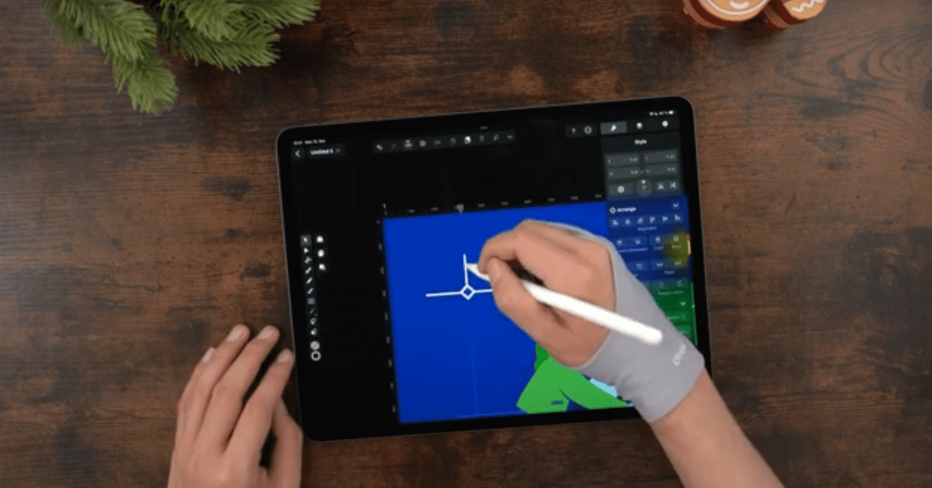 Male hands drawing on an iPad positioned on a wooden table