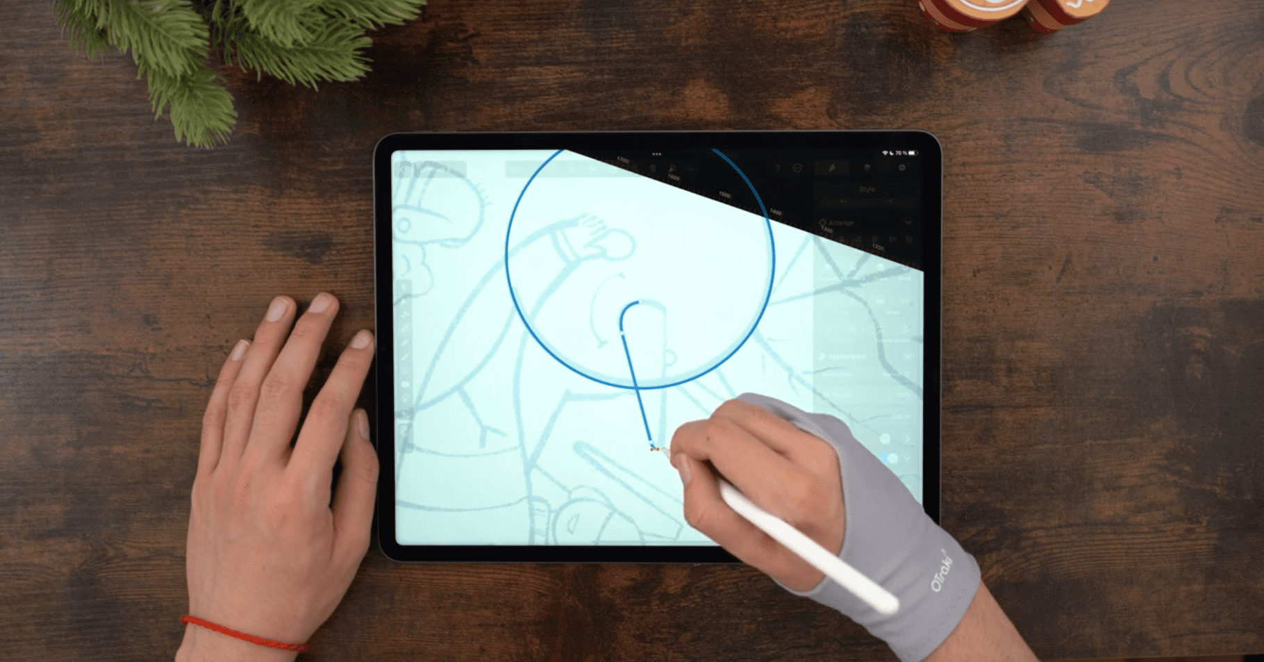 Male hands drawing on an iPad positioned on a wooden table