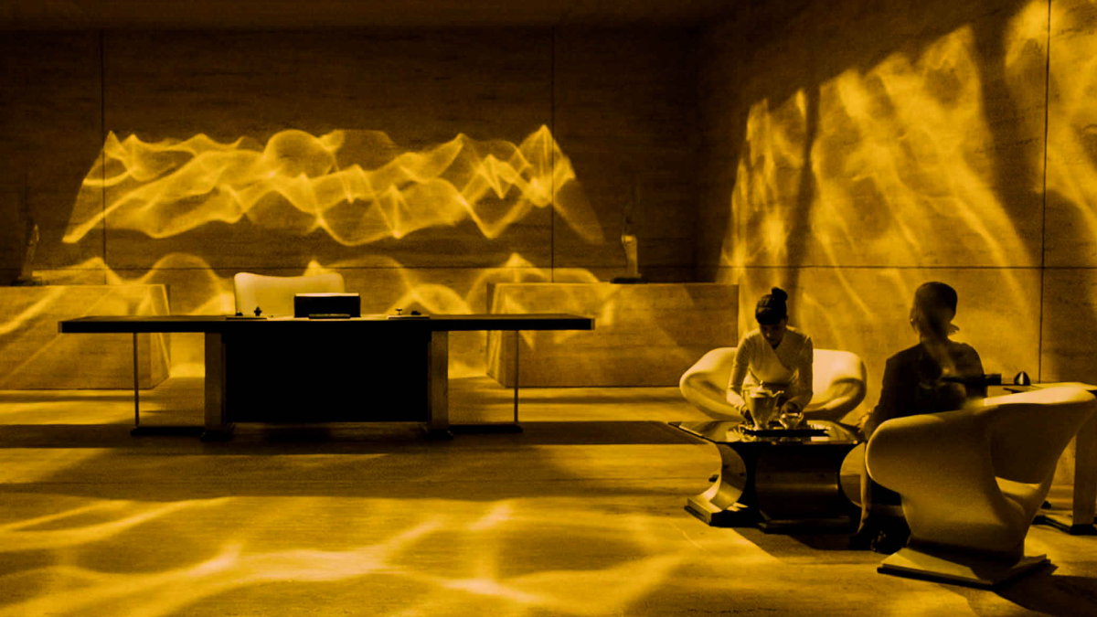 Woman and man sitting in a yellow-lit office with light reflexes