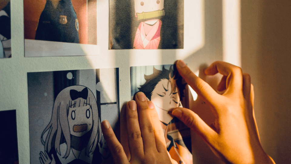 Person sticking photos of anime characters on a wall